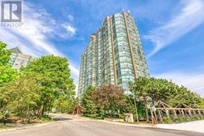 Mississauga (Erin Mills) condo for rent - A tall glass building stands in front of a tree-lined street.