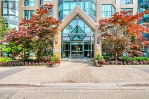 Mississauga (Erin Mills) condo for rent - The front of a building with a glass entrance and a stone archway.