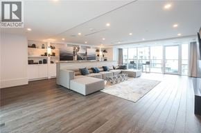 Grimsby condo for rent - A spacious living room with a white sofa set and a wooden floor.