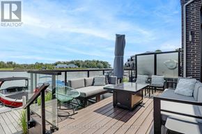 Innisfil townhouse for rent - A wooden deck with a glass table and chairs overlooking a body of water.