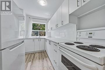 Hamilton (Durand) condo for rent - A white kitchen with a stove top oven and a refrigerator.