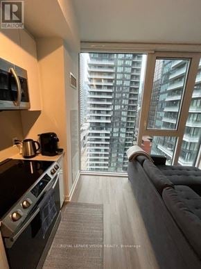 Toronto (Waterfront Communities) condo for rent - A modern kitchen with a stove top oven and a couch.