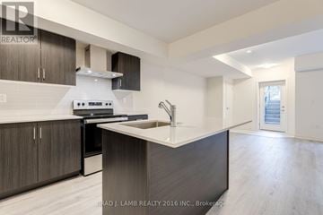 Richmond Hill (Mill Pond) townhouse for rent - A modern kitchen with dark wood cabinets and a white range hood.