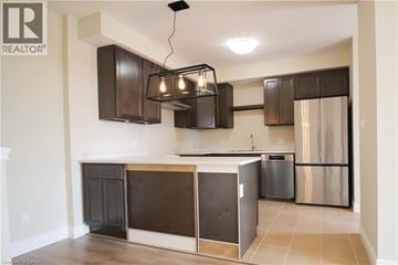 Kitchener townhouse for rent - A kitchen with a black and brown island and stainless steel refrigerator.