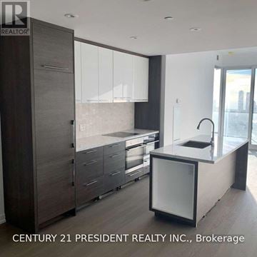 Toronto (University) condo for rent - A modern kitchen with a large island and a refrigerator with a glass door.