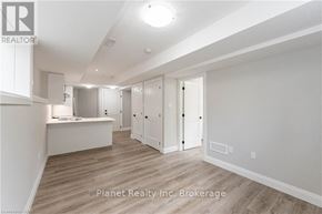 Guelph (Exhibition Park) apartment for rent - A spacious room with wooden flooring and white walls, featuring a desk and a row of cupboards.