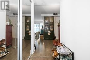 Toronto (Bay Street Corridor) condo for rent - A room with a glass door leading to another room with a shoe rack in the foreground.