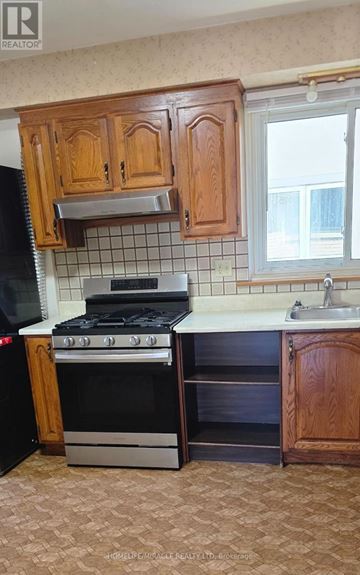 Toronto (Wexford-Maryvale) apartment for rent - A black stove and oven in a kitchen with wooden cabinets.