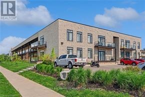 Brantford condo for rent - A modern building with a parking lot in front.