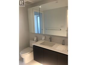 Richmond apartment for rent - A white bathroom with a toilet, sink, and mirror.