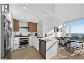 Burnaby apartment for rent - A modern kitchen with a refrigerator on the left and a dining table with a glass top in the center.