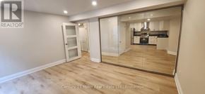 Oakville (Ro River Oaks) apartment for rent - A spacious room with a mirrored wall and wooden flooring.