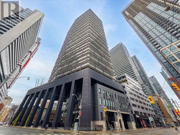Toronto (Waterfront Communities) condo for rent - A tall building with a black facade stands in front of other skyscrapers.