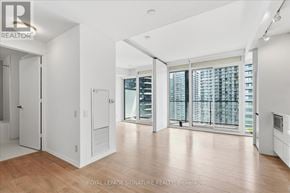 Toronto (Waterfront Communities) condo for rent - A spacious room with wooden floors and a view of a cityscape through the windows.
