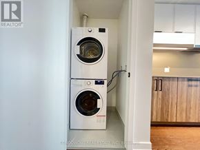 Toronto (Forest Hill South) condo for rent - A white washing machine is installed in a narrow space between two walls.