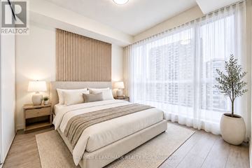 Toronto (Willowdale East) condo for rent - A bedroom with a large bed, a nightstand with a lamp, and a potted plant.