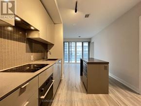 Toronto (Bay Street Corridor) condo for rent - A modern kitchen with a stove top oven and a range hood.
