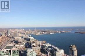 Toronto (Waterfront Communities) condo for rent - A cityscape with a body of water in the foreground and buildings of various sizes.