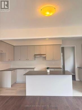 Pickering townhouse for rent - A kitchen with a white island and wooden floors.
