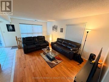 Brampton (Fletcher's Meadow) apartment for rent - A living room with black leather couches and a wooden floor.