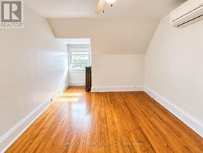 Toronto (Humewood-Cedarvale) triplex for rent - A room with wooden floors and a window with curtains.