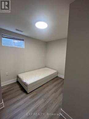 Toronto (L'amoreaux) apartment for rent - A bedroom with a bed, wooden floors, and a window.