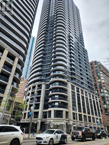 Toronto (Church-Yonge Corridor) condo for rent - A tall building with many windows stands in the middle of a street with cars and people.