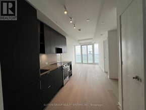 Mississauga (City Centre) condo for rent - A modern kitchen with black cabinets and a wooden floor.