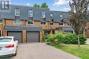 Toronto (Hillcrest Village) townhouse for rent - A white car is parked in front of a brick building with a garage door.