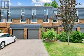 Toronto (Hillcrest Village) townhouse for rent - A white car is parked in front of a brick building with a garage door.