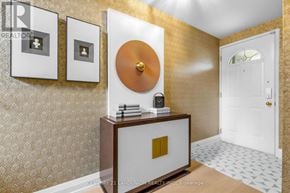 Toronto (Hillcrest Village) townhouse for rent - A hallway with a white door, a gold circular object on the wall, and a wooden cabinet with a gold square on it.