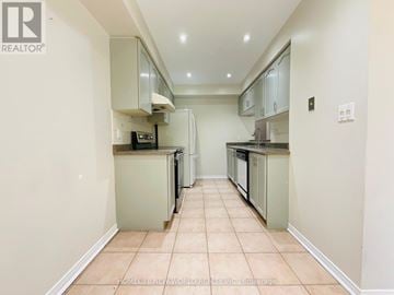 Toronto (Malvern) townhouse for rent - A kitchen with white cabinets and a tiled floor.