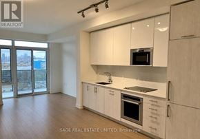 Toronto (Waterfront Communities) condo for rent - A modern kitchen with white cabinets and a view of the city.
