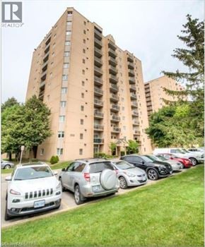 London condo for rent - A tall apartment building with cars parked in front.