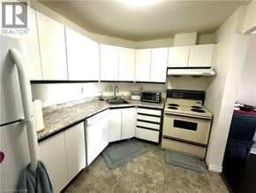 London condo for rent - A kitchen with white cabinets and a granite counter top.