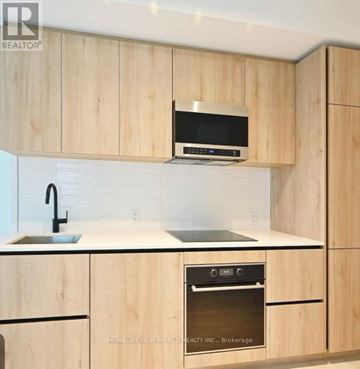 Toronto (Mount Pleasant West) condo for rent - A kitchen with wooden cabinets and a black microwave above the stove.