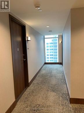 Toronto (Waterfront Communities) condo for rent - A hallway with a carpeted floor and a door on the left.