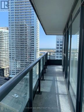 Toronto (Waterfront Communities) condo for rent - A balcony with glass railings overlooks a cityscape.