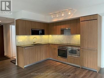 Toronto (Waterfront Communities) condo for rent - A modern kitchen with wooden cabinets and a central island.