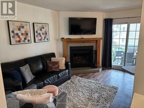 Blue Mountains townhouse for rent - A living room with a black couch, a fireplace, and a television.