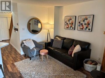 Blue Mountains townhouse for rent - A living room with a black couch, a round mirror, and two paintings on the wall.