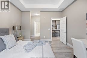 Tecumseh condo for rent - A bedroom with a bed, nightstand, and chair.