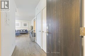 Toronto (Kensington-Chinatown) condo for rent - A hallway with a door on the right and a couch in the background.