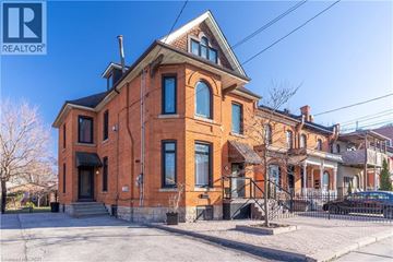 Hamilton apartment for rent - A red brick house with a black car parked in front.