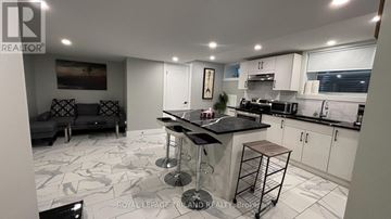 Central Elgin (Port Stanley) fourplex for rent - A modern kitchen with a bar stool and a black countertop.