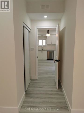 Newmarket (Woodland Hill) apartment for rent - A hallway with a door on the left and a kitchen in the distance.