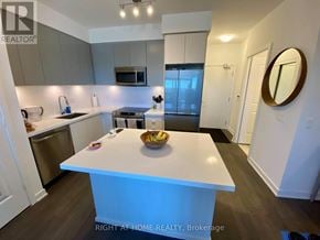 Mississauga (Central Erin Mills) condo for rent - A kitchen with a white island and a bowl of fruit on it.