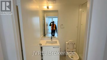 Brampton (Fletcher's Creek South) condo for rent - A bathroom with a sink, toilet, and a person in the background.
