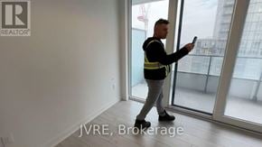 Brampton (Fletcher's Creek South) condo for rent - A man in a high visibility vest is holding a tablet in a room with a view of a construction site outside the window.