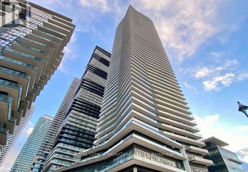 Toronto (Mimico) condo for rent - A tall building with a curved facade stands out against a clear sky.